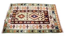 A modern Kilim wool rug with geometric design. Of brown, orange and green ground.