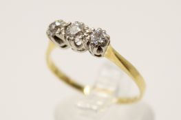 An 18ct gold and three stone diamond ring. The central round cut stone circa 0.