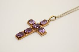 A 9ct gold and amethyst cross pendant on a yellow metal chain.