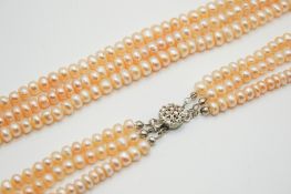 A triple strand of pale pinky-cream freshwater pearls.