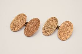 A pair of 9ct gold cuff links. Of oval form, with engraved scroll decoration, hallmarked.