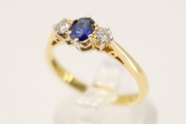 A hallmarked 18ct gold three stone ring. Set with one oval faceted sapphire of 0.