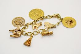 A gold charm bracelet with eight gold and yellow metal charms.