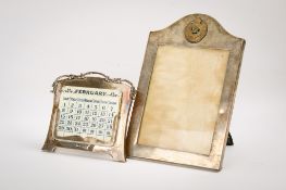 A silver desk calendar and a silver photograph frame.