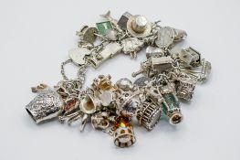 A silver charm bracelet with numerous silver and white metal charms.