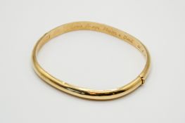 A yellow metal hollow hinged bangle.