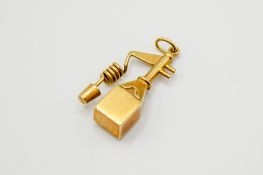 A yellow metal pendant in the form of an oil can or water pump.