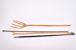 A group of three walking sticks and a natural wooden hay fork.