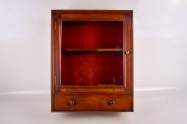 An early 20th century wall mounted mahogany glazed wall cabinet. Having a drawer beneath cupboard.