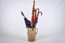 A vintage pottery jug containing nine umbrellas and walking sticks.
