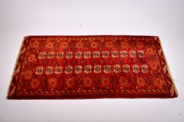 An Afghan style wool rug on a red ground.