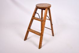 A vintage folding wooden stool. Having a circular top and two steps, H60cm.