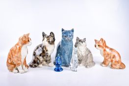 A collection of seven ceramic or glass cats figurines.