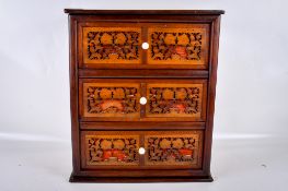 A small wooden chest of drawers with blind fretwork decoration.