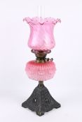 An early 20th century oil lamp with pink shade.
