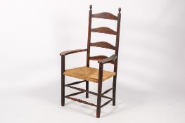 A rustic antique wooden ladderback open armchair. Having a rush work seat.