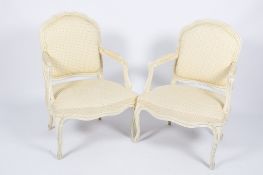 A pair of 20th century French antique style carved and painted open armchairs.