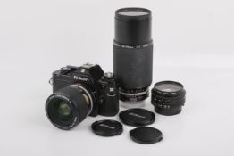 A Nikon EM 35mm SLR camera outfit. Black. Serial number 6881103. With three lenses; a Nikon 50mm f1.