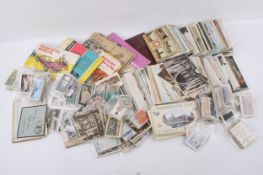 A collection of assorted vintage postcards and cigarette trading cards.