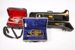 A group of three cased brass musical instruments.