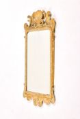 A giltwood and gesso wall mirror in George II style. Shell and scroll decoration, bevel edge glass.