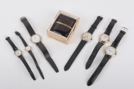 Six assorted wristwatches and a vintage alarm clock.