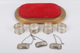 Four silver napkin rings and three silver decanter labels.