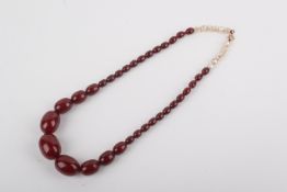 A 'cherry amber' Bakelite beaded necklace. Graduated oval beads, the largest bead width 2.
