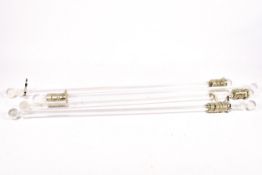 A set of four contemporary clear plastic curtain poles. With curtain rings.