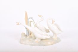 A Lladro porcelain model of three duck amongst reeds.