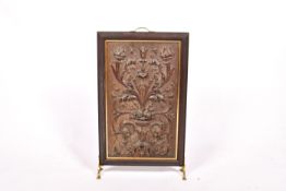 A fire screen with carved wooden panel and brass fittings. High relief carving of foilage.