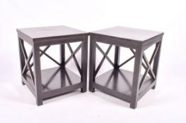 A pair of contemporary black side tables with X-shaped side frames and a lower shelf.