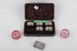 A pair of silver mounted pots, silver napkin rings, and a silver matchbox case.