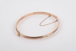A 9ct rose gold hinged bangle. With engraved scrolling decoration, 4.8g.