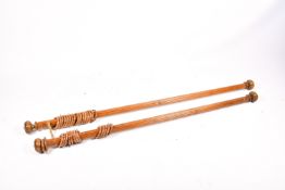 Two fluted wooden curtain poles with curtain rings.