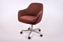 A vintage brown upholstered office tub chair. Raised on a metal mobile base.