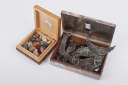 A collection of assorted hard stones and white metal decorative elements.