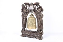 A carved Chinese hardwood stand with brass bell.