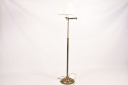 A solid brass telescopic swing arm standard lamp raised on a circular base.