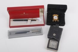 Two boxed ballpoint pens and two small clocks.