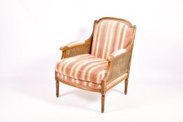 A French bergere mahogany style armchair with stripped pink and cream upholstery.