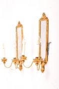 A pair of contemporary antique style two-light wall sconces. With mirror backs and gilt finish.