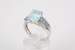 A white metal dress ring set centrally with one rectangular cushion cut topaz.