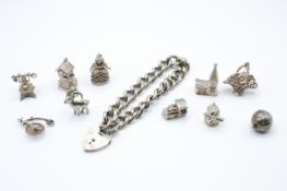A hallmarked sterling silver curb link bracelet and ten charms of various designs. 80.