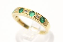 A hallmarked 18ct gold dress ring. Set with round faceted emeralds of 0.
