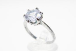 A white metal moissanite solitaire ring. The round cut stone circa 9.