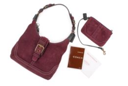 A purple suede Coach shoulder bag and matching purse.