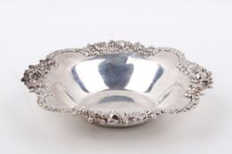 A white metal silver dish stamped 'Stirling'. Having lobed and ornate floral rim.