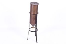 A vintage copper percolator water filter on a tripod stand.