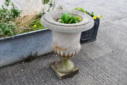 A two piece reconstituted stone urn with a wide rim, on a short base. Total H68cm.